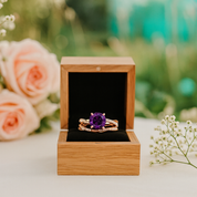Amethyst ring in a wooden box with flowers in the background
