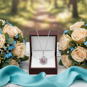 Bouquets of roses and a necklace with a heart pendant on a wooden surface in a forest setting.