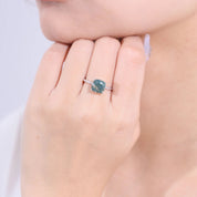 Close-up of a hand wearing a ring with a blue gemstone on a light background