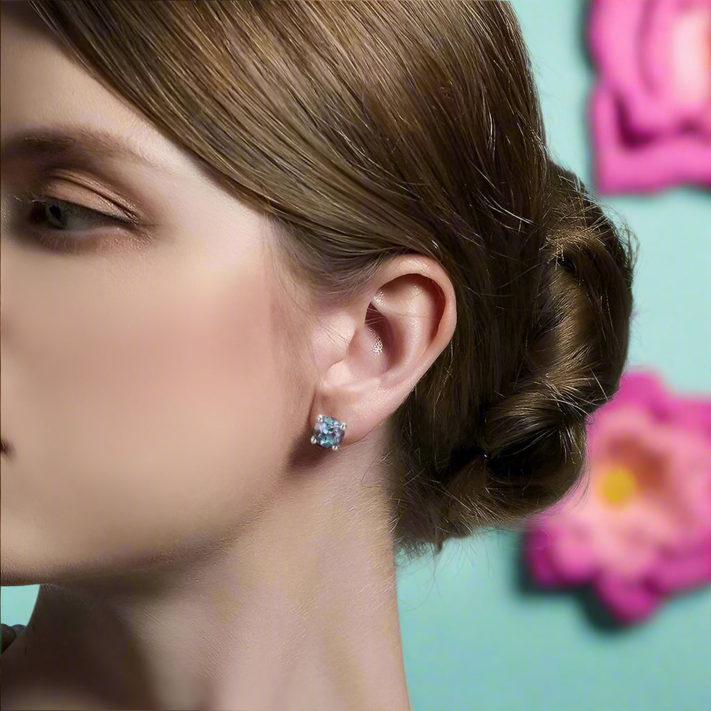 Close-up of a woman wearing blue gemstone earrings with a neutral background