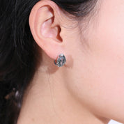 Close-up of an ear wearing a silver earring with a gemstone.