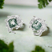 Pair of silver earrings with green gemstones on a white background