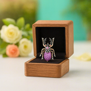 Decorative brooch in a wooden box with flowers in the background