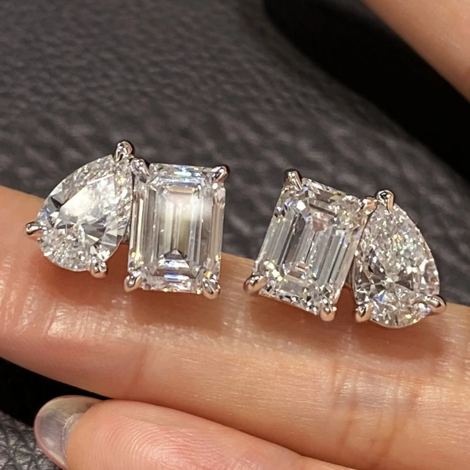 Diamond earrings displayed on a finger against a dark background