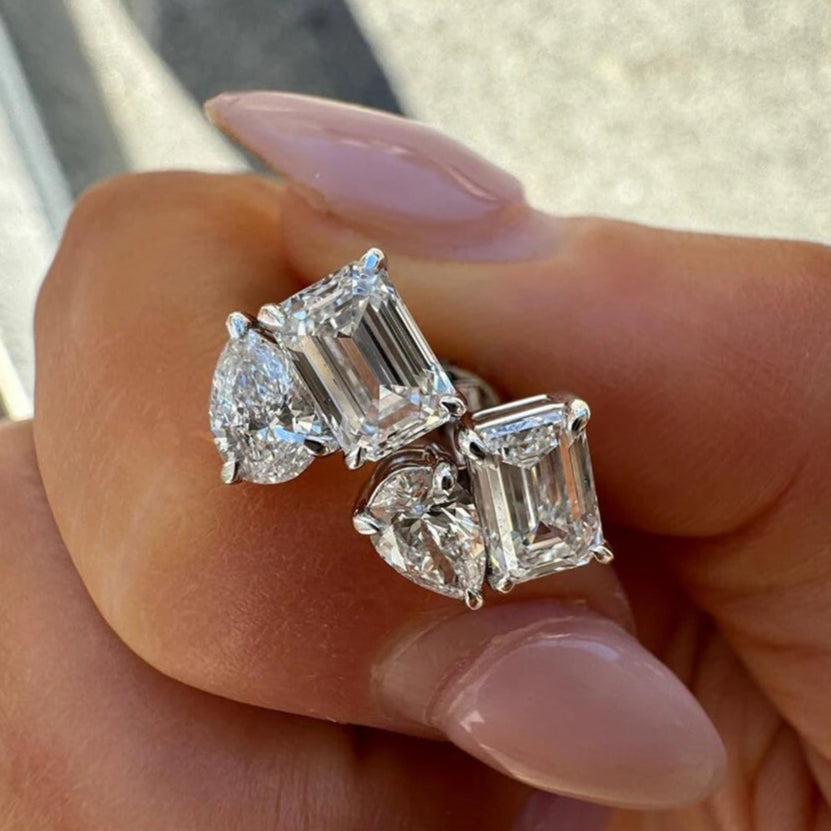 Diamond earrings held in a hand with a neutral background
