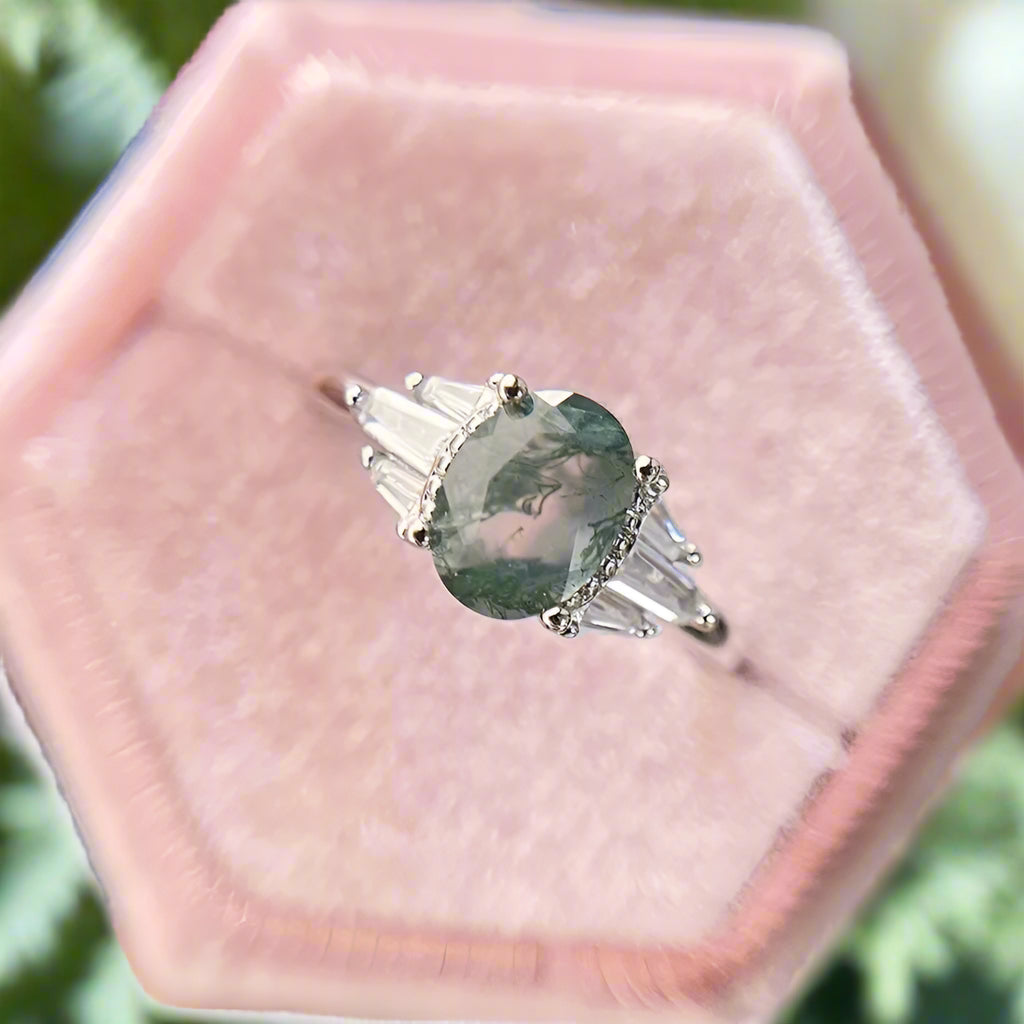 Diamond ring with a green gemstone in a pink velvet box