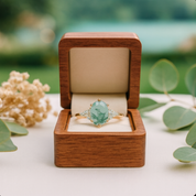 Green gemstone ring in a wooden box with a natural background