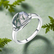 Silver ring with a green gemstone on a white background