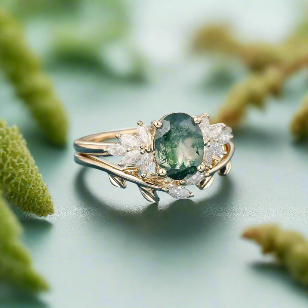 Gold ring with a green gemstone and diamonds on a blue surface with blurred dried flowers in the background