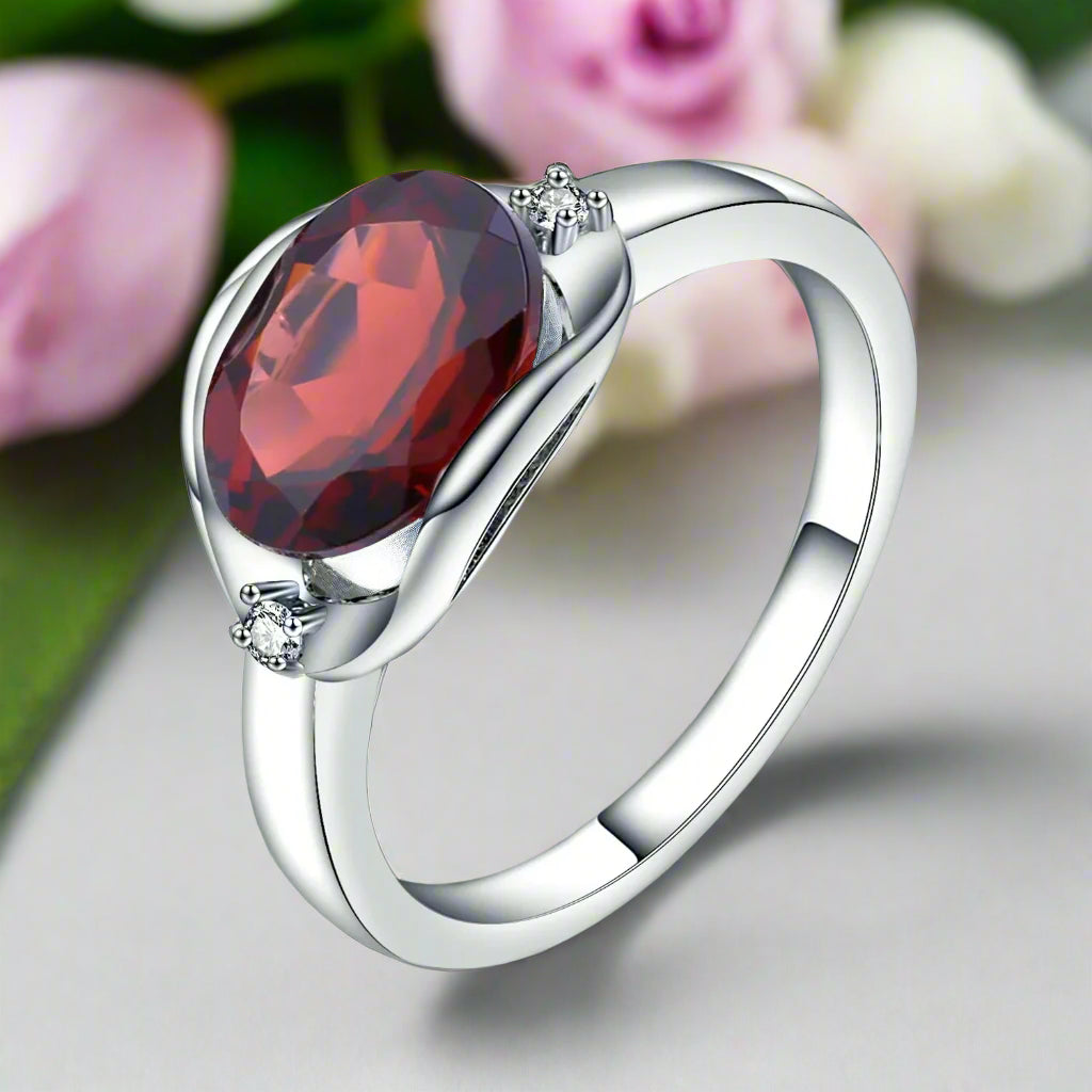 Silver ring with a red gemstone on a white background