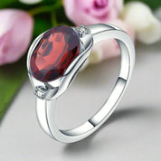 Silver ring with a red gemstone on a white background