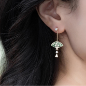 Earring worn by a person with dark hair, close-up view.