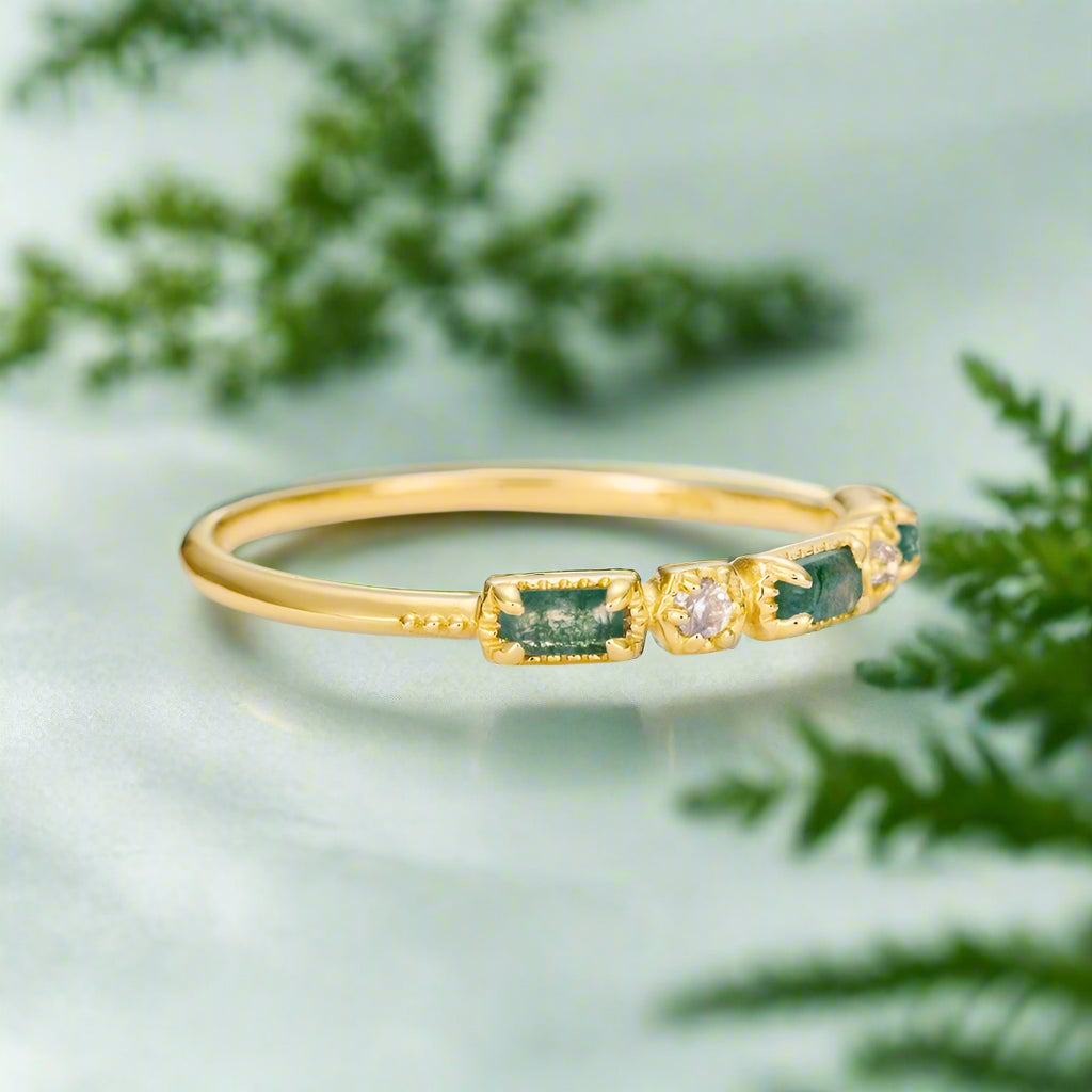 Gold bracelet with green gemstones on a light gray background