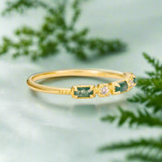 Gold bracelet with green gemstones on a light gray background