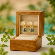 Gold earrings in a wooden box with a natural background