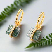 Gold earrings with green stone and diamond accents on a white background