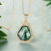 Gold necklace with a green gemstone pendant on a white background