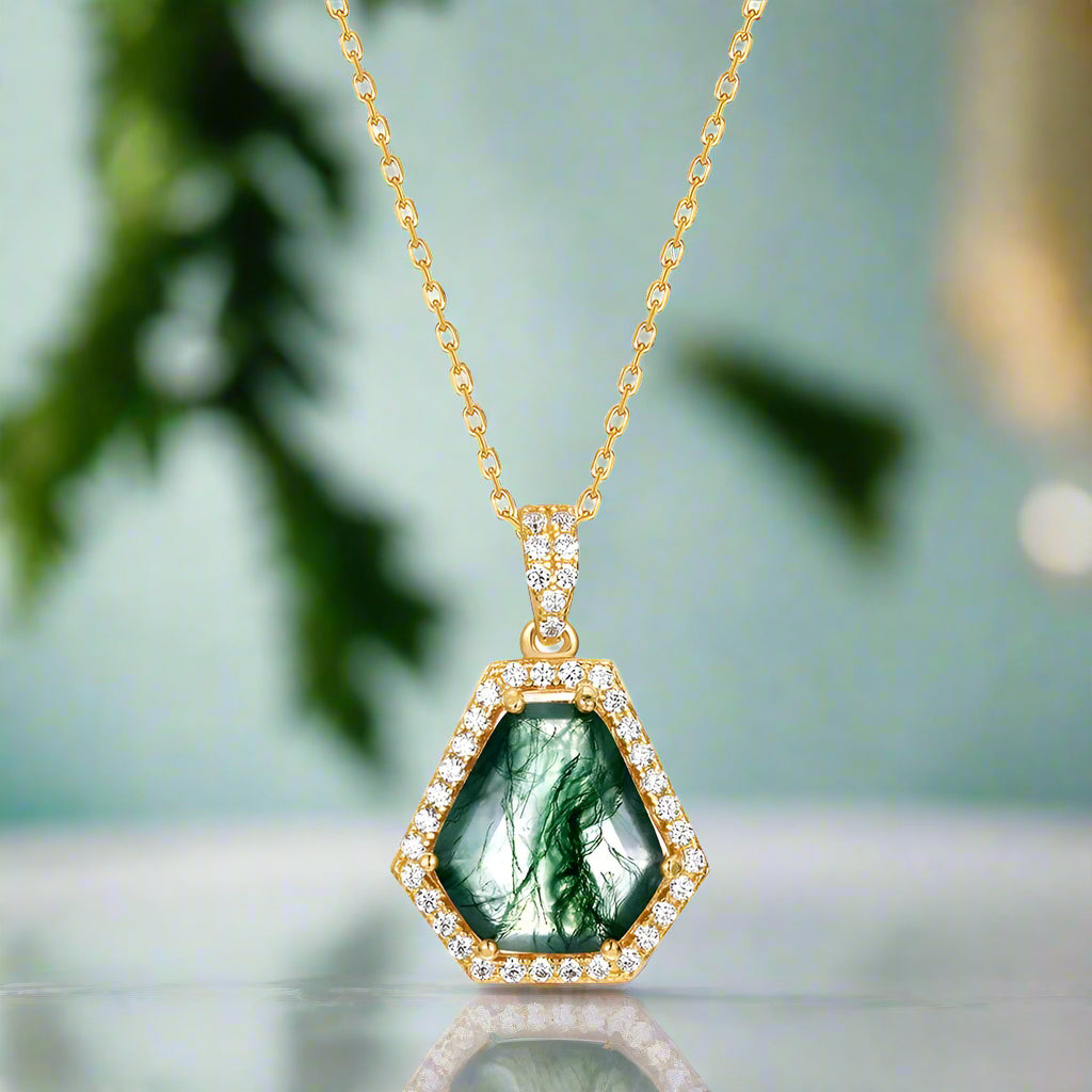 Gold necklace with a green pendant on a white background