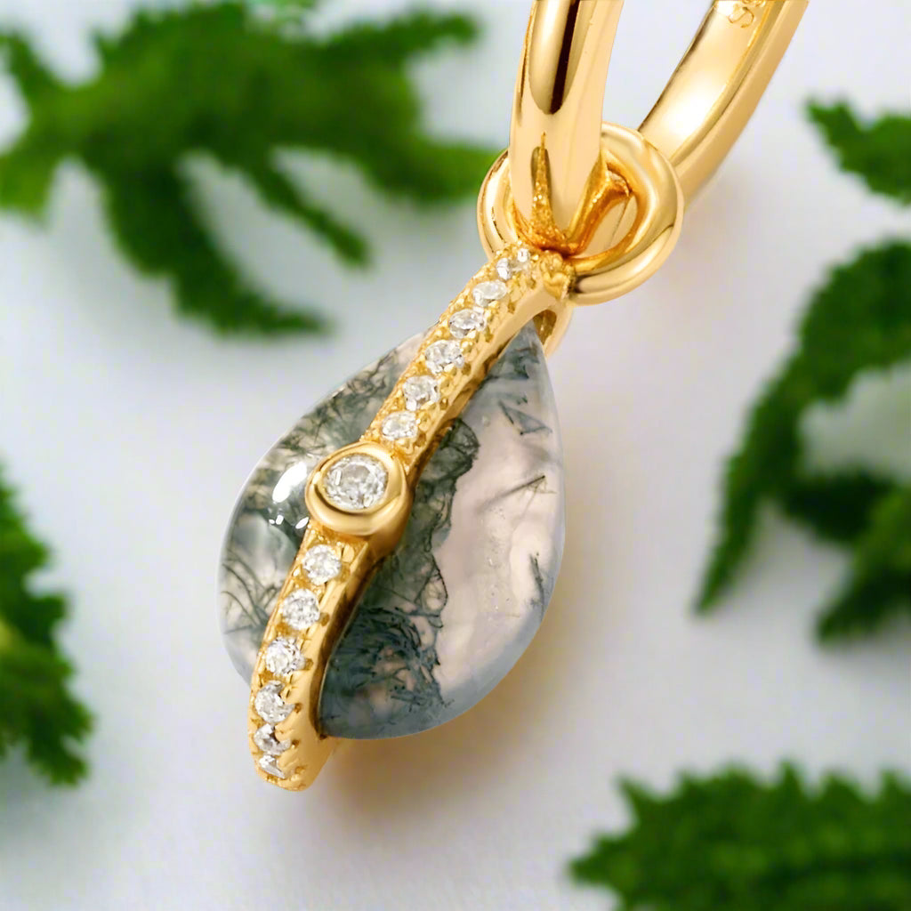 Gold pendant with a central gemstone and smaller stones on a light gray background