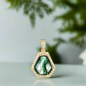 Gold pendant with green gemstone and diamond accents on a white background