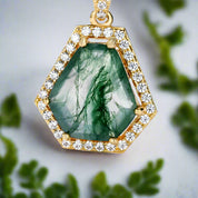 Gold pendant with green gemstone and diamonds on a white background