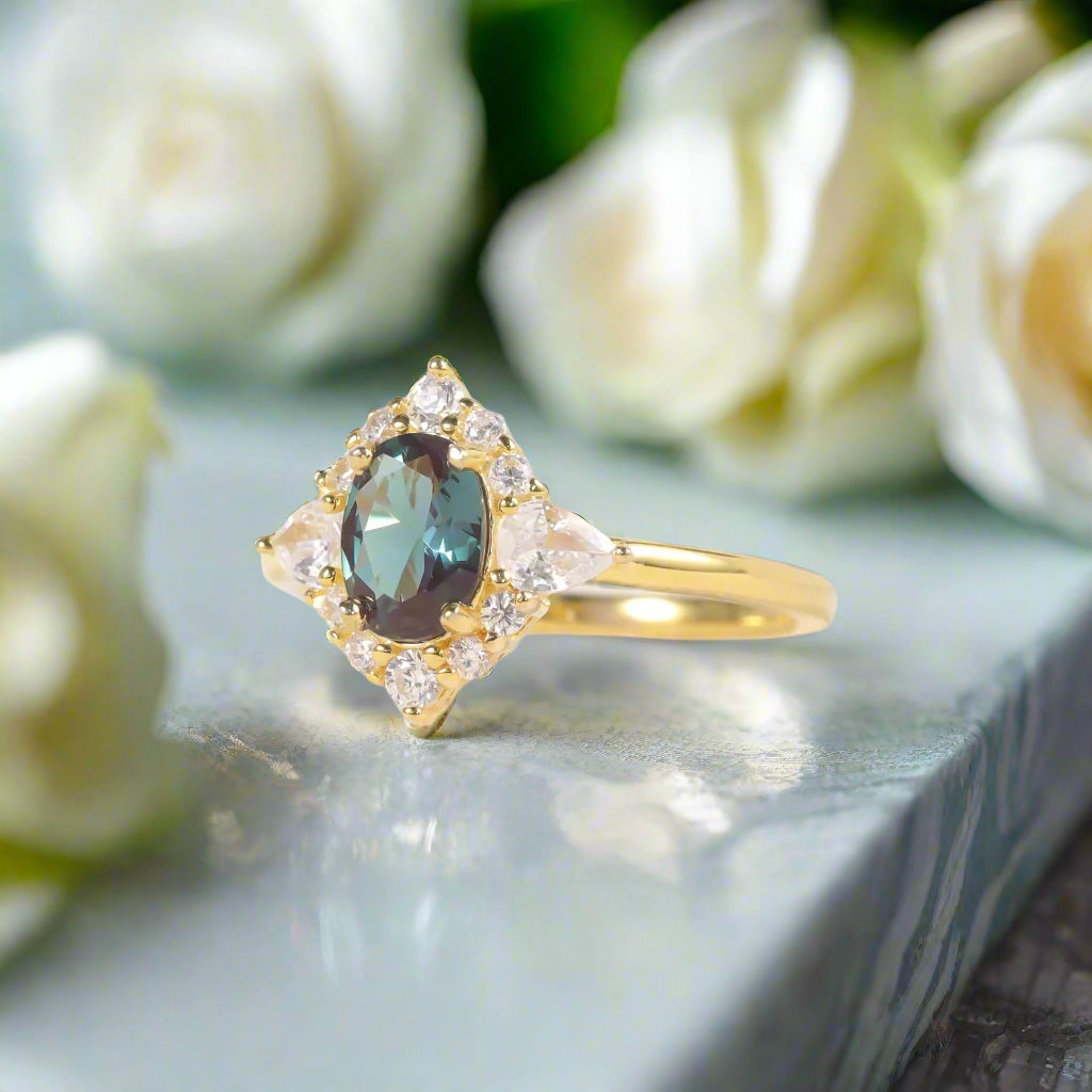 Gold ring with a blue gemstone and diamond accents on a soft white background