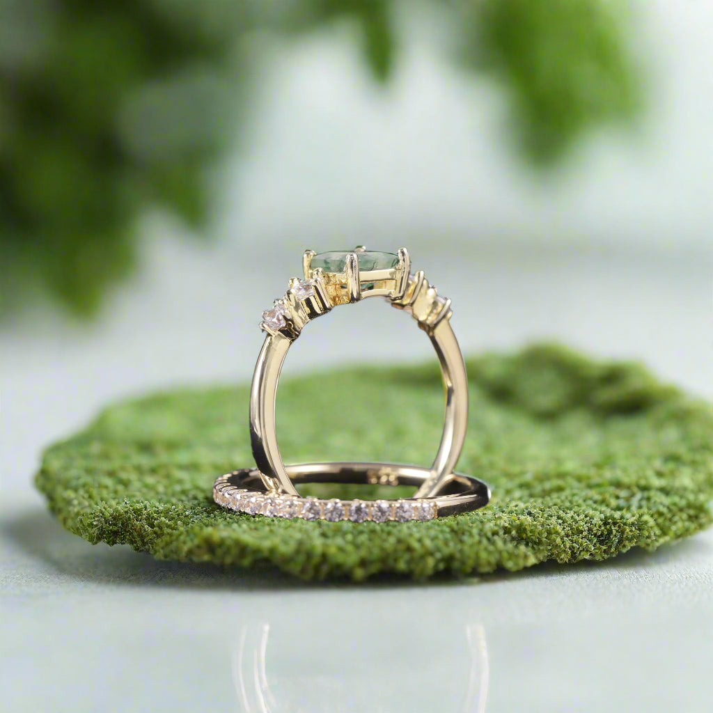Gold ring with a green gemstone and diamond accents on a dark background