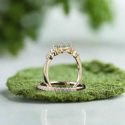 Gold ring with a green gemstone and diamond accents on a dark background