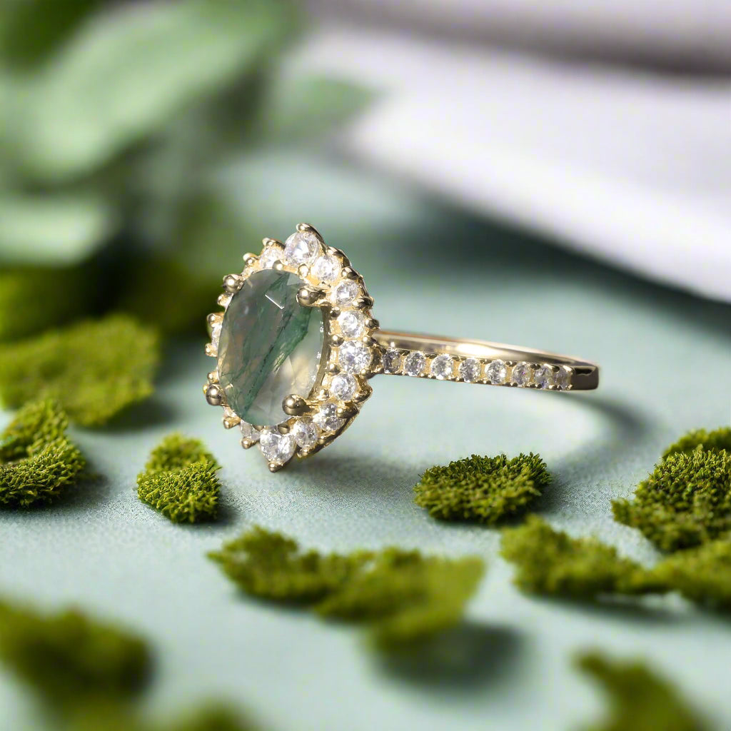 Gold ring with a green gemstone and diamond accents on a dark surface