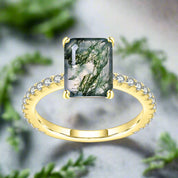 Gold ring with a green gemstone and diamond accents on a white background