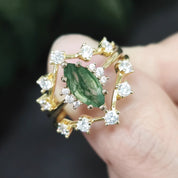 Gold ring with a green gemstone held on a blurred background