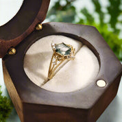 Gold ring with a green gemstone in a wooden jewelry box