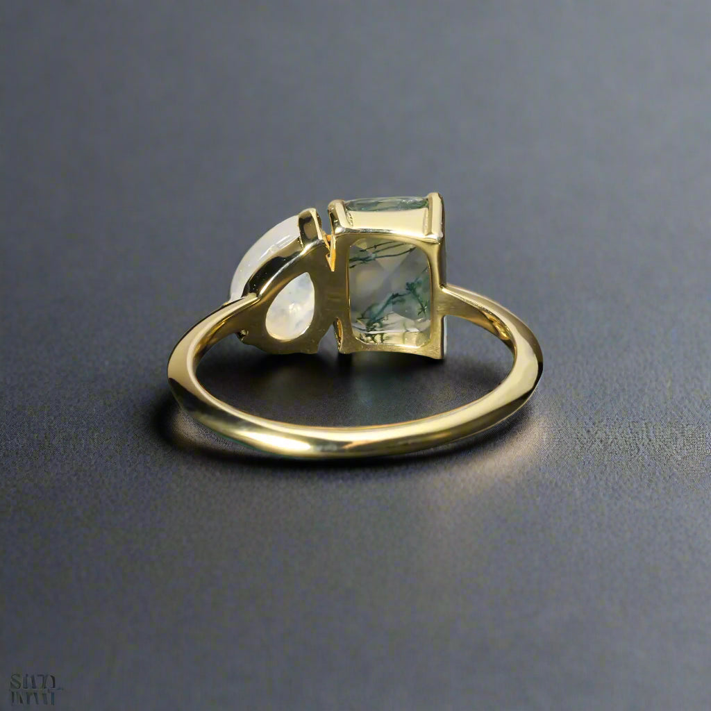 Gold ring with a green gemstone on a dark surface