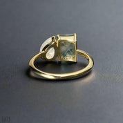 Gold ring with a green gemstone on a dark surface