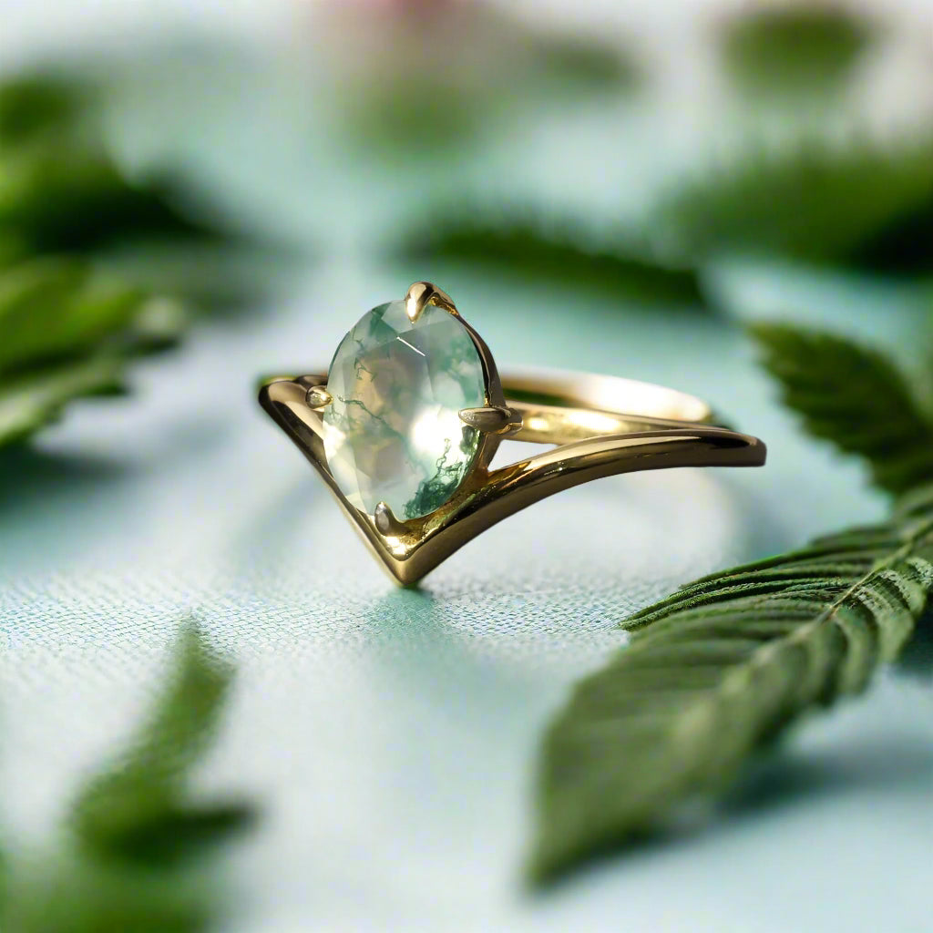Gold ring with a green gemstone on a dark surface