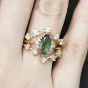 Gold ring with a green gemstone on a person's finger against a dark background