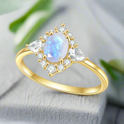 Gold ring with a teardrop-shaped gemstone and smaller diamonds on a white background