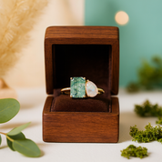 Gold ring with green gemstone in a wooden box on a blurred natural background