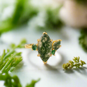 Gold ring with green gemstones on a natural background