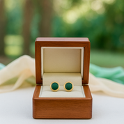Green cufflinks in a wooden box with a blurred green background