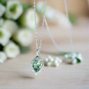 Green gemstone necklace on a light blue background.