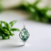 Green gemstone pendant with silver frame on white background