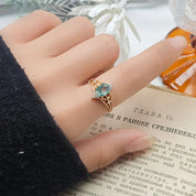 Hand wearing a gold ring with a blue gemstone on an open book