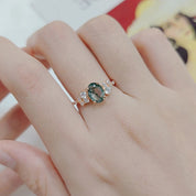 Hand wearing a ring with a green gemstone on a blurred background