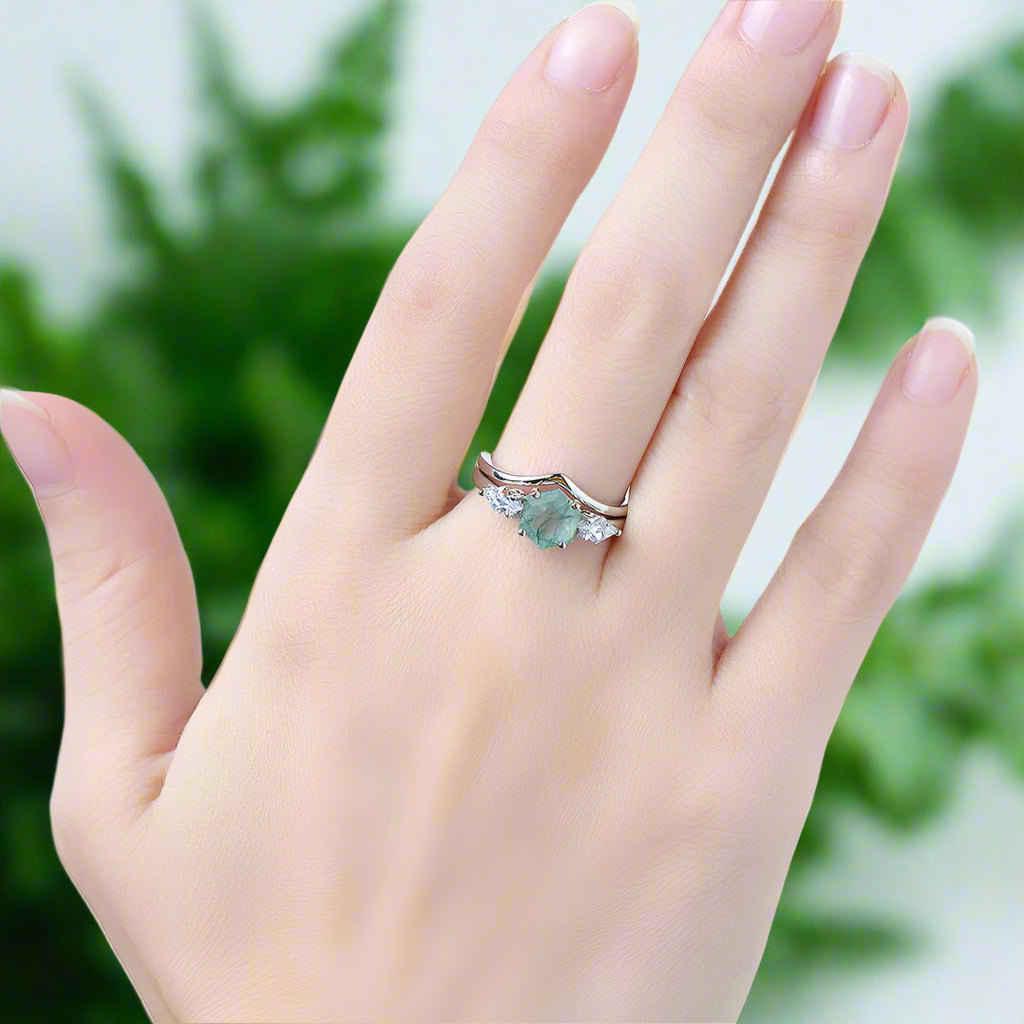 Hand wearing a ring with a green gemstone on a blurred background