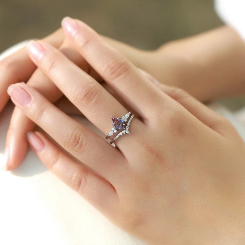Hand wearing a ring with a purple gemstone on a blurred background