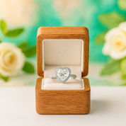 Heart-shaped diamond ring in a wooden box with flowers in the background