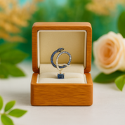 Jewelry box with a blue and gold ring inside, surrounded by flowers.