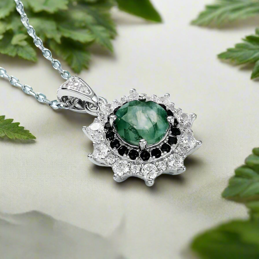Jewelry pendant with green gemstone and black stones on a light blue background