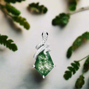 Jewelry pendant with green stone and snake design on a white background